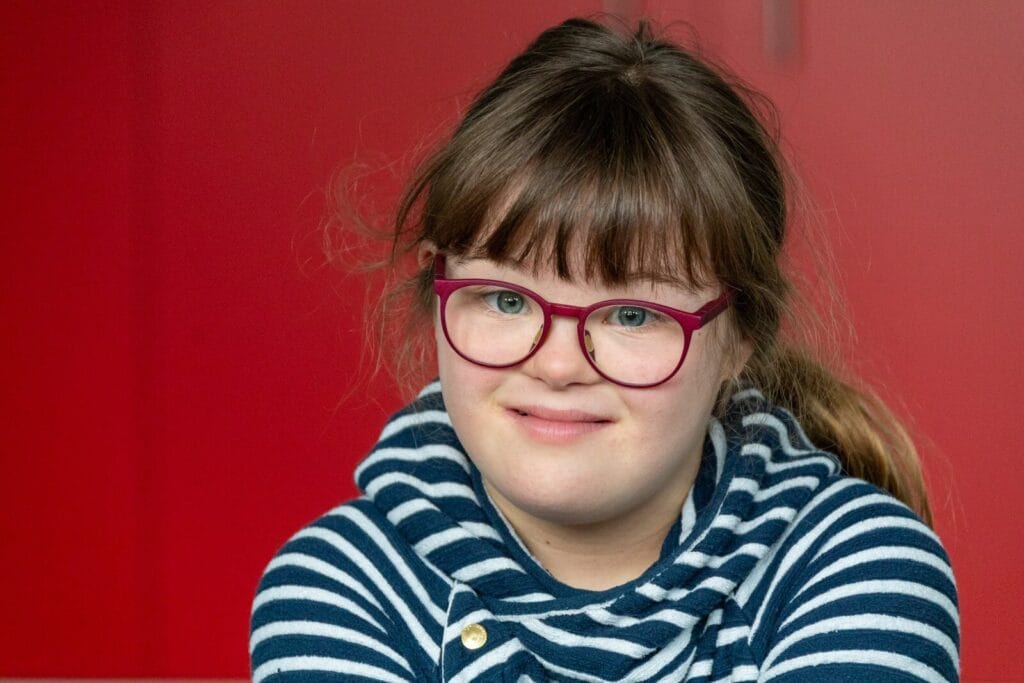 Mädchen mit roter Brille und gestreiftem Pulli