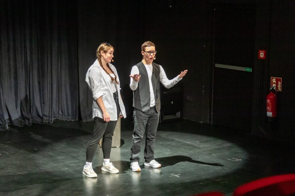 zwei Mitglieder der einsmehr Gruppe FreiSpiel21 auf der Bühne