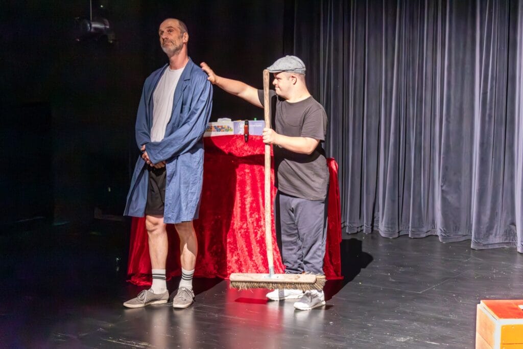 einsmehr Gruppe FreiSpiel21, zwei Männer auf der Bühne mit Besen