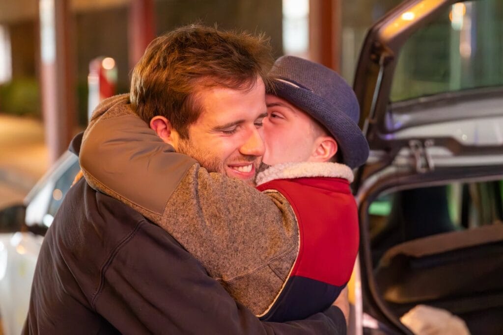 Mitglied der Gruppe Gästeliste einsmehr und Betreuer umarmen sich