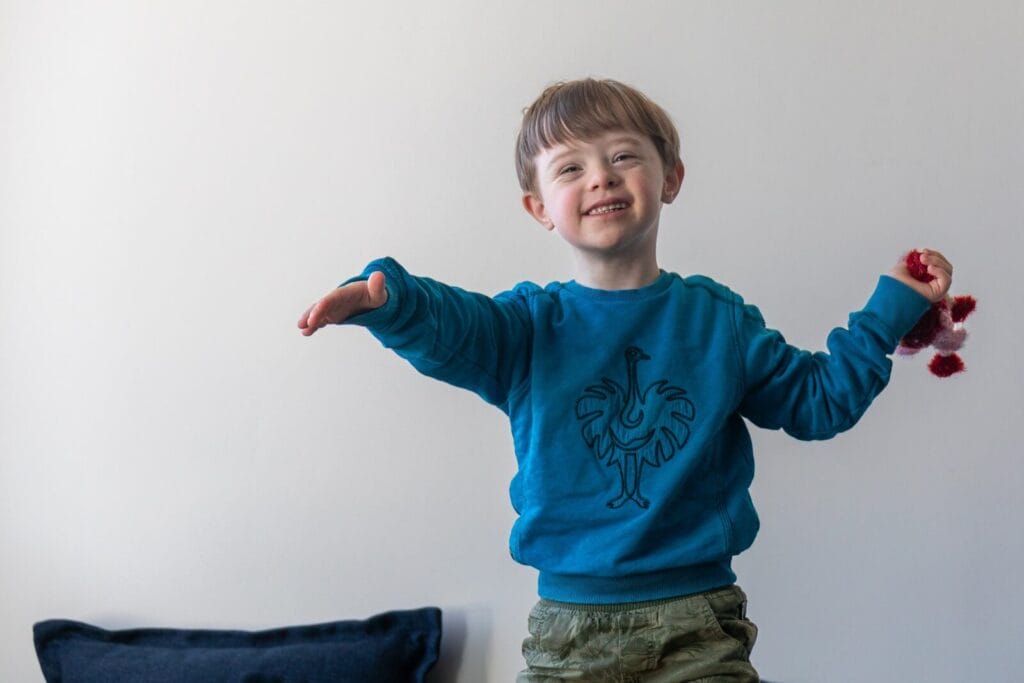 Junge mit blauem Pulli lächelt und wirft