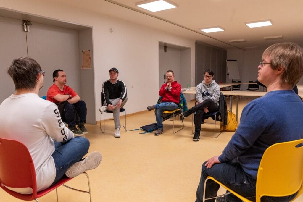 Die einsmehr Männergruppe sitzt im Stuhlkreis zusammen