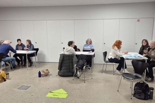 einsmehr AK Wohnen sitzt in Gruppen um Tische